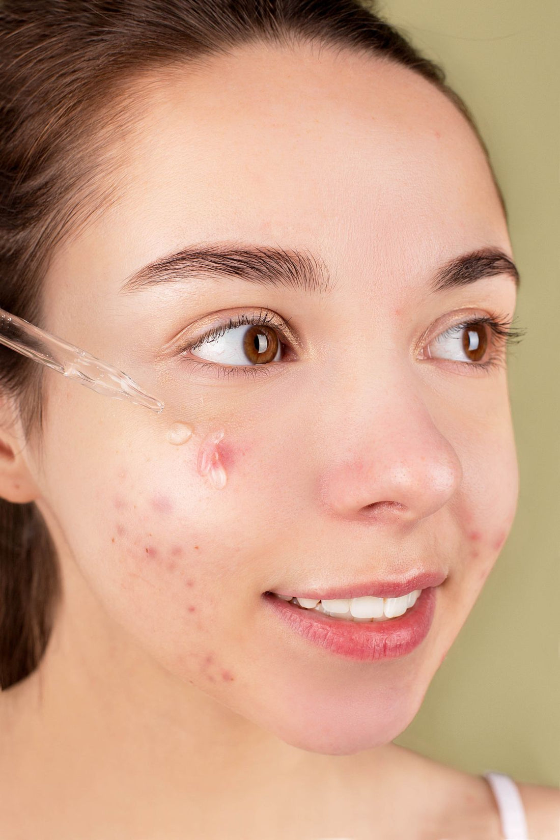 Close-up of a woman applying facial serum to smooth, hydrated skin