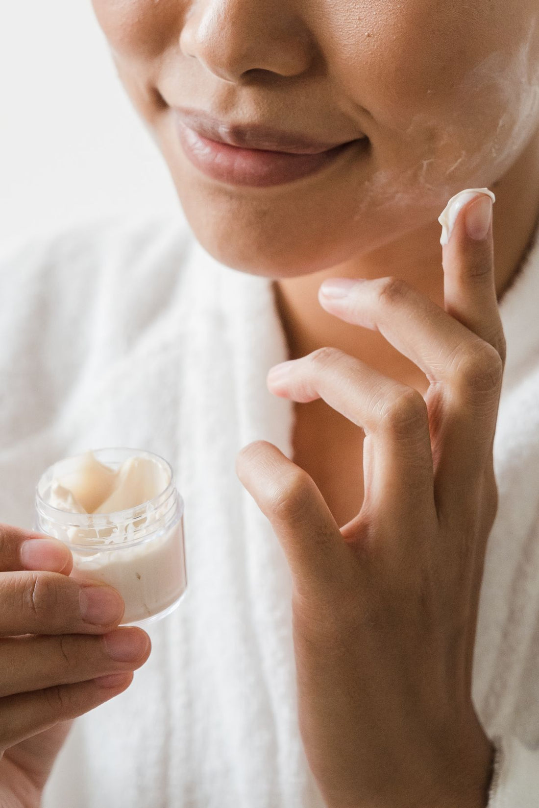 Close-up of a woman applying moisturiser to her cheek during a winter to spring skincare routine